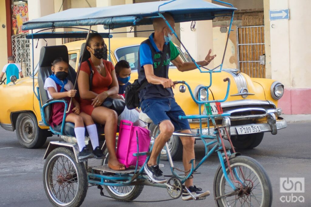 Una madre lleva a sus hijos a la escuela en un bicitaxi, en La Habana. Foto: Otmaro Rodríguez.