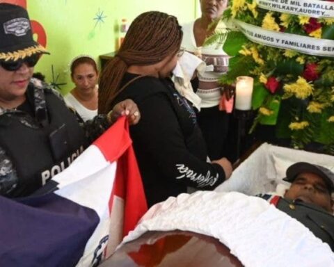 Daughter of Captain Williams Méndez Ramírez, Wilkary Méndez, observes the corpse of her father when he was veiled at his home in the Las Cañitas sector of the capital, a Police delegation wraps the coffin with the National Flag.  Manolito Jimenez