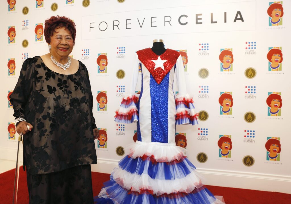 Irma Peñalver posa al lado de la famosa bata que ella confeccionó para Celia Cruz. Foto cortesía de Celia Cruz Legacy Project.