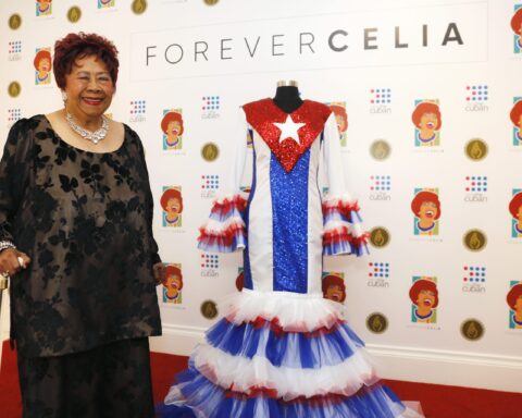 Irma Peñalver posa al lado de la famosa bata que ella confeccionó para Celia Cruz. Foto cortesía de Celia Cruz Legacy Project.