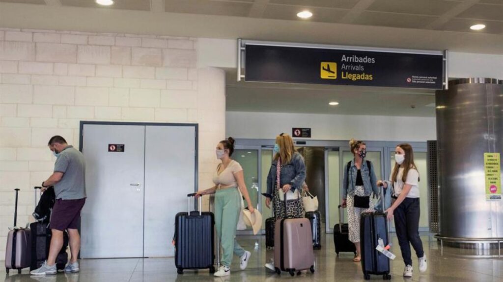 Turistas con nasobucos llegan al aeropuerto de Menorca en un vuelo procedente de Londres. Foto: EFE.