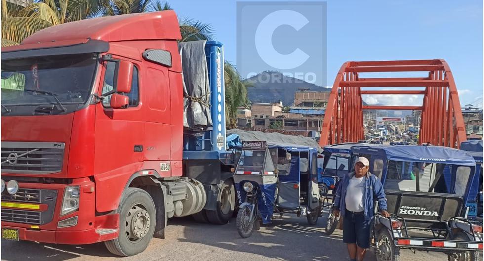 Heavy cargo carriers block the entrance bridge to the Pichanaqui district