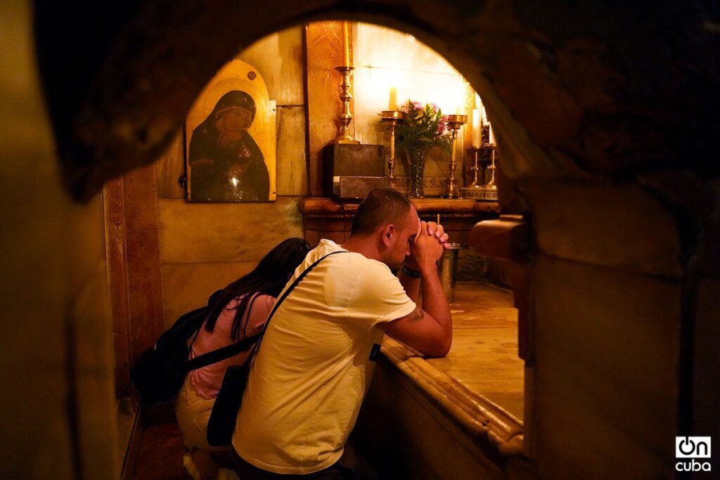 Una pareja de palestinos cristianos oran frente a la tumba de Jesús de Nazaret.