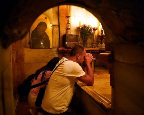 Una pareja de palestinos cristianos oran frente a la tumba de Jesús de Nazaret.