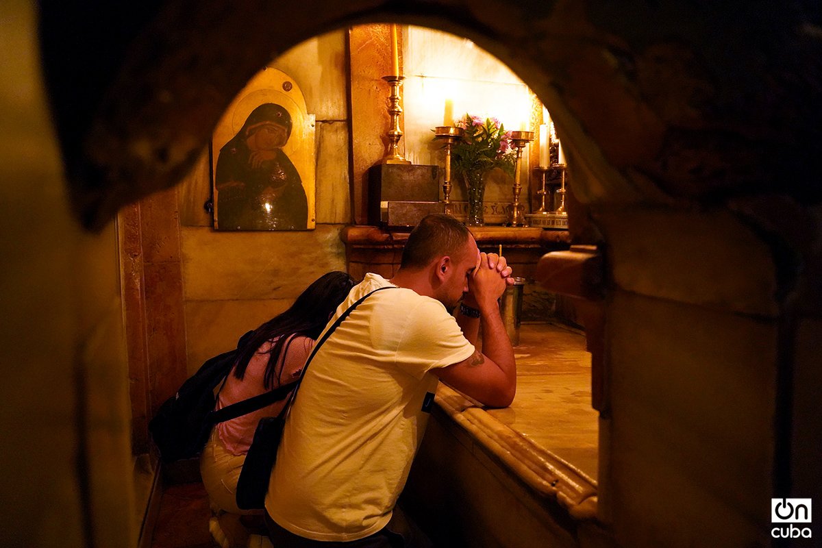 Una pareja de palestinos cristianos oran frente a la tumba de Jesús de Nazaret.