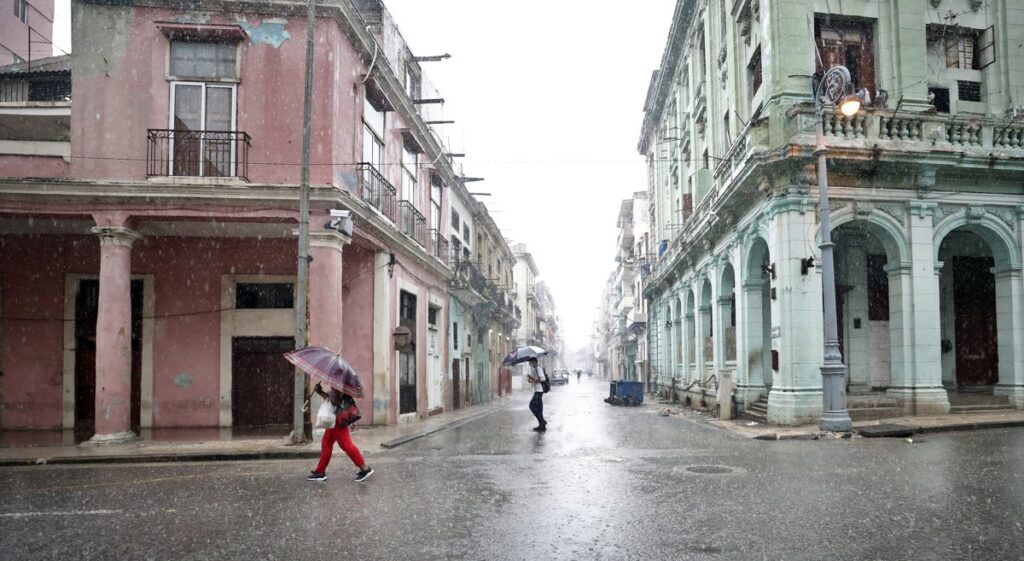 Varias personas caminan por una calle bajo un fuerte aguacero en La Habana (Cuba).  Foto: Ernesto Mastrascusa/Efe.