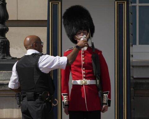 Un policía británico refresca a un miembro de la Guardia Real. Foto: Yahoo.