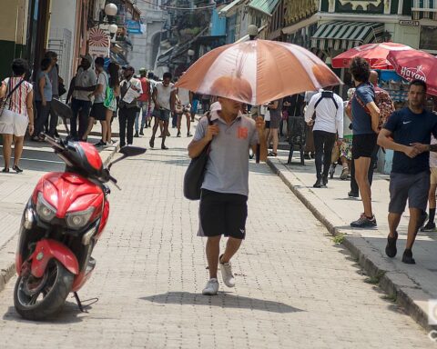 Un hombre se protege del sol con una sombrilla, en la calle Obispo de La Habana. Foto: Otmaro Rodríguez.