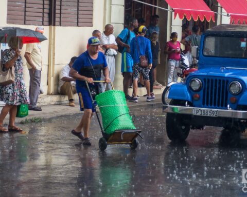 Personas en una calle de La Habana durante una lluvia de verano. Foto: Otmaro Rodríguez.