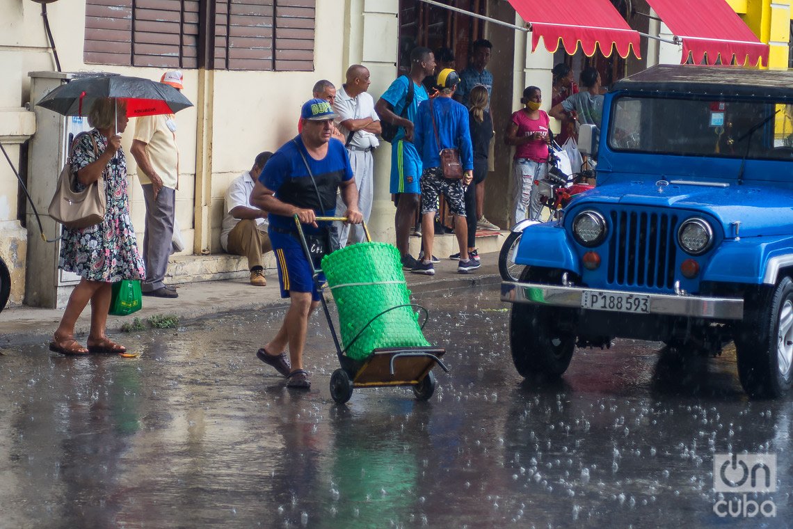 Personas en una calle de La Habana durante una lluvia de verano. Foto: Otmaro Rodríguez.