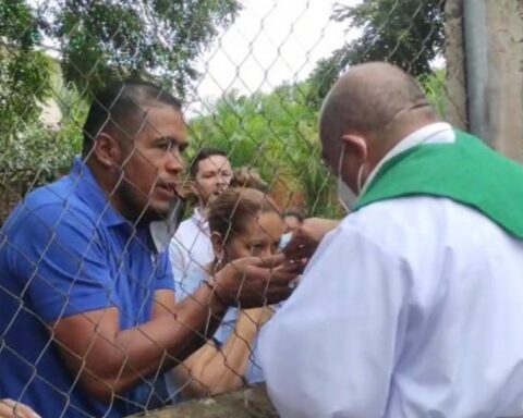 Priest officiates mass through a mesh before police blockade