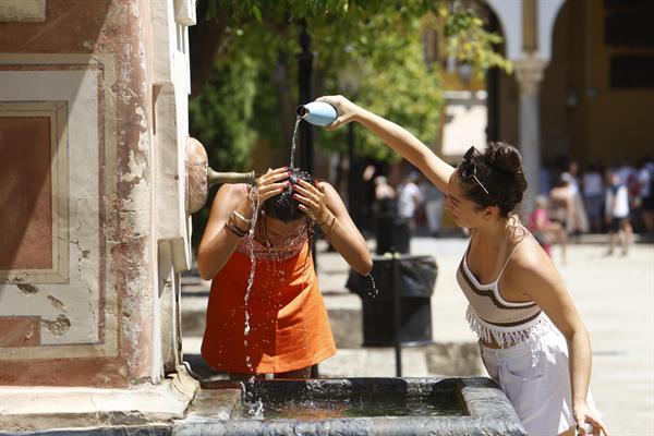 Dos mujeres se refrescan en una fuente del Patio de los Naranjos de la Mezquita Catedral de Córdoba. EFE/Salas