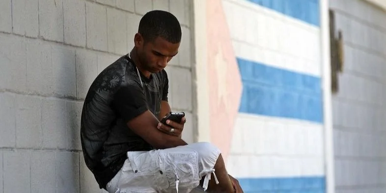 Un joven conectado a internet a través de su teléfono celular, en Cuba