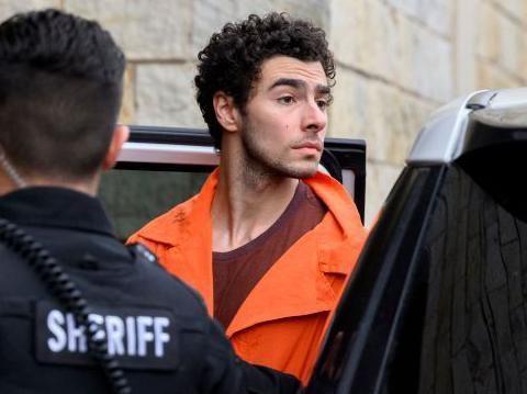 Luigi Mangione, the man accused of murdering UnitedHealth CEO Brian Thompson, arrives for a hearing in a Pennsylvania court. He wears an orange prison uniform.