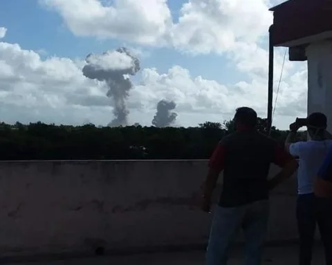 Tres personas observan la columna de humo provocada por la explosión en el almacén militar de Melones, en Holguín, Cuba