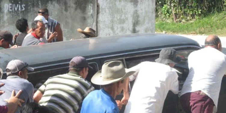 Cubanos empujando un carro fúnebre