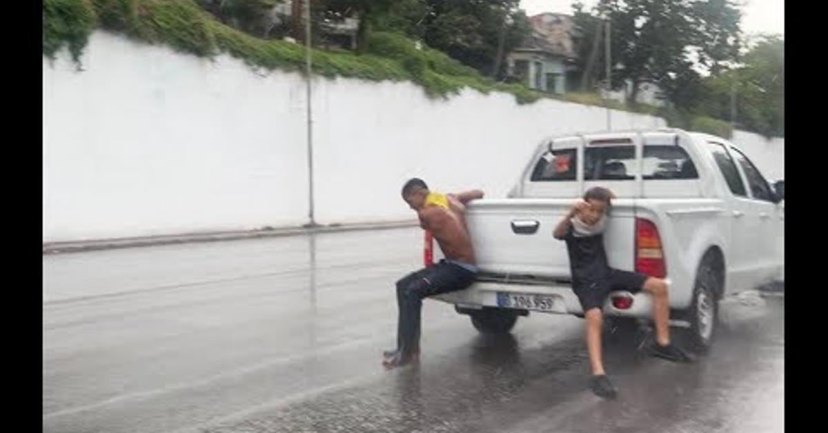 Danger in the streets! Children cling to cars during rains in Havana