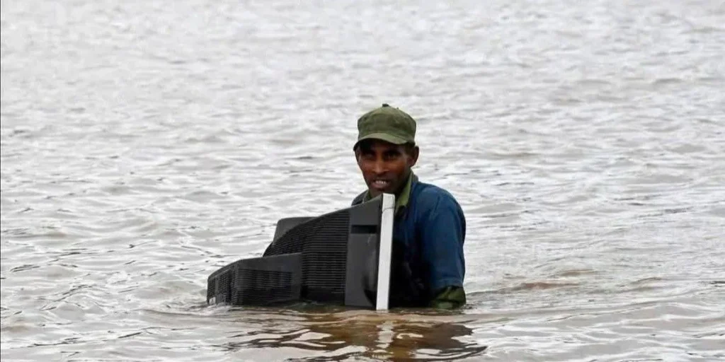 Un hombre que quedó aislado por las inundaciones en la provincia de Holguín sostiene su televisor, ya inservible