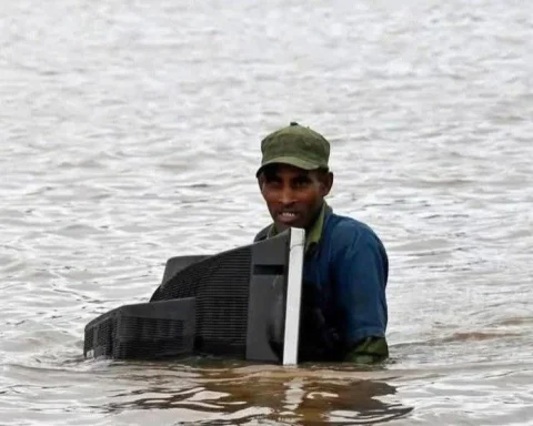 Un hombre que quedó aislado por las inundaciones en la provincia de Holguín sostiene su televisor, ya inservible