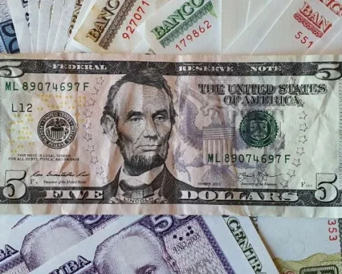 Un billete de cinco dólares sobre decenas de billetes de pesos cubanos
