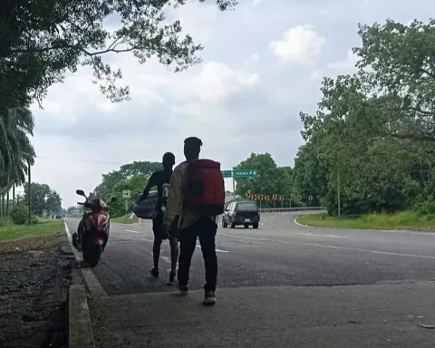 Pequeños grupos de migrantes cubanos avanzan a pie por una carretera costera rumbo al norte de México