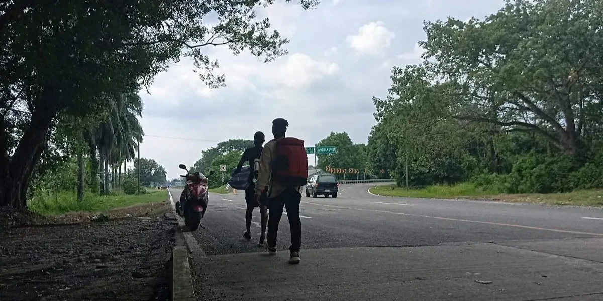 Pequeños grupos de migrantes cubanos avanzan a pie por una carretera costera rumbo al norte de México