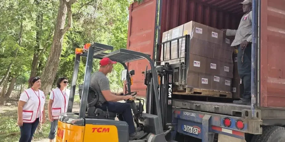 Dos miembros de Cáritas Cuba supervisan el traslado de la ayuda humanitaria